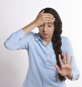 Photograph of a woman showing discomfort or stress to illustrate, "The Keto Flu: Symptoms, Causes, And Remedies".