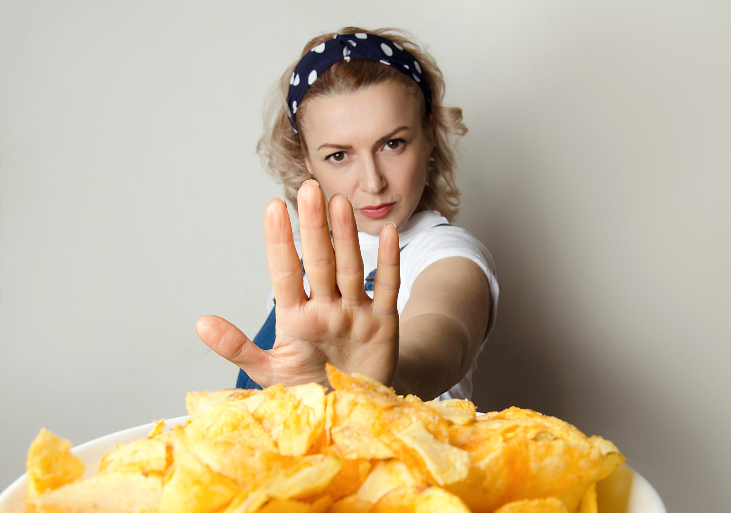 Photograph of a woman holding her hand to say no to junk food used to illustrate, "". Click to learn about getting a customized keto diet plan designed based on your activity level, food preferences, weight goals, and other personal criteria.
