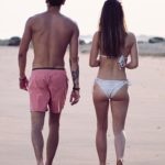 Couple walking away from camera on a beach during summer vacation. Click to learn about getting a customized keto diet plan designed based on your activity level, food preferences, weight goals, and other personal criteria.