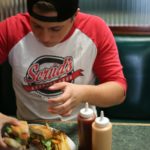Teenage boy eating a hamburger fast food meal. Click to learn about getting a customized keto diet plan designed based on your activity level, food preferences, weight goals, and other personal criteria.