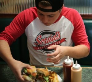 Teenage boy eating a hamburger fast food meal. Click to learn about getting a customized keto diet plan designed based on your activity level, food preferences, weight goals, and other personal criteria.
