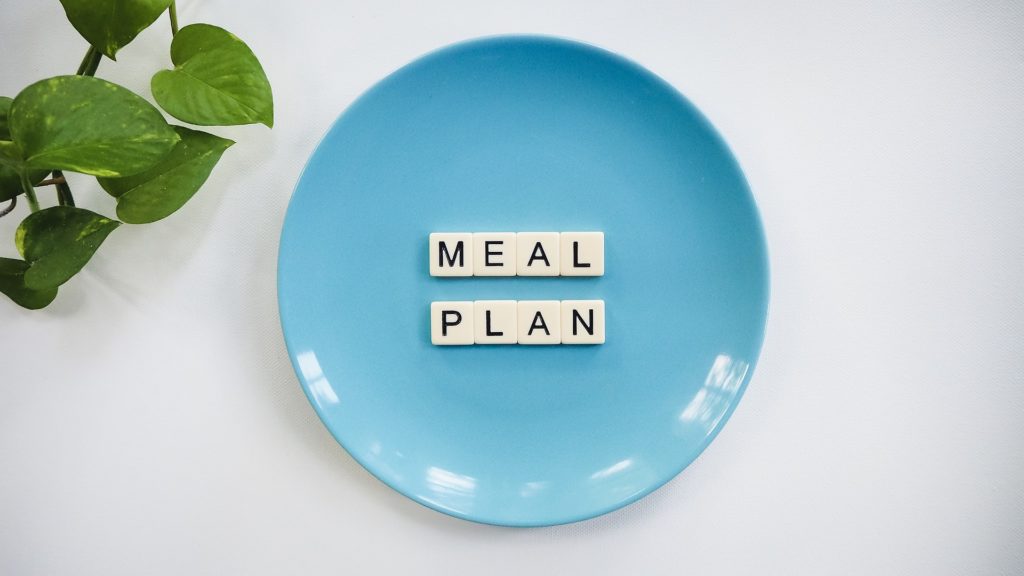 Photograph of a blue plate with tiles spelling "meal plan" on it used to illustrate, "Meal Planning Is The Key To Keto Success".